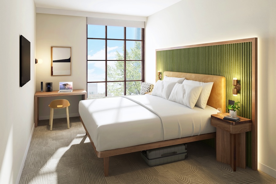 A modern hotel room with a green-accented headboard, large windows and a minimalist workspace.