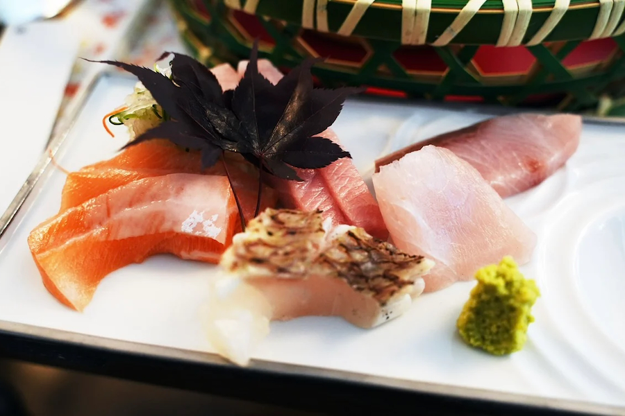 A beautifully plated assortment of fresh sashimi garnished with a maple leaf.