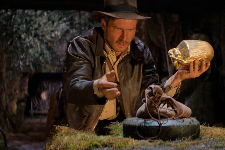 Explorer in a fedora carefully swapping a golden idol with a sandbag in a jungle temple setting.