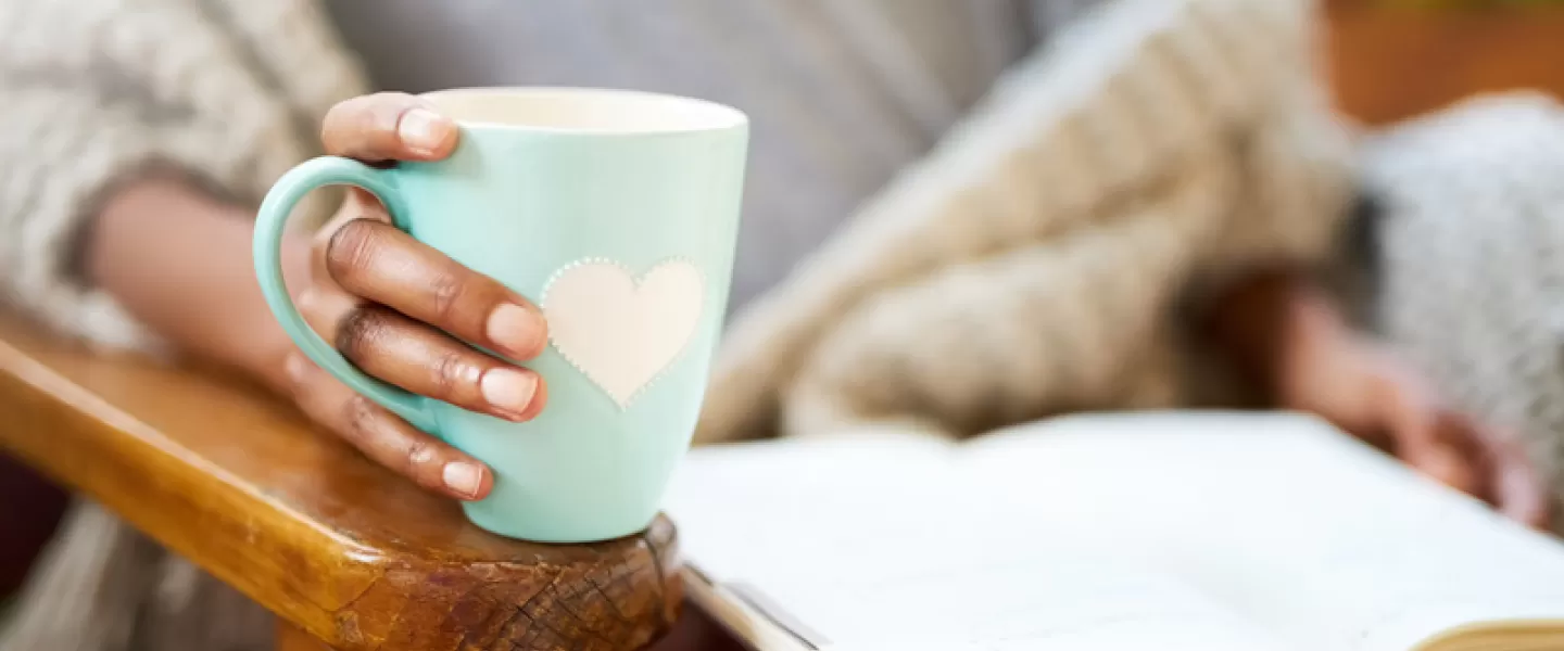 Woman holding mug and reading a book