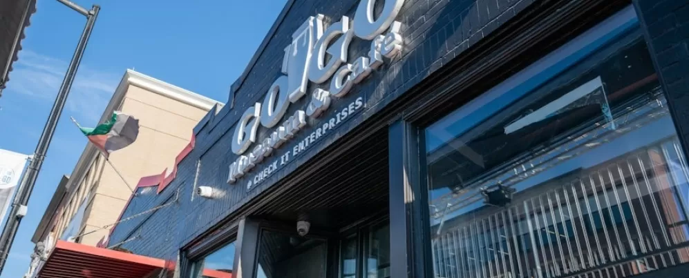 The entrance to the Go-Go Museum & Café features bold signage on a black-painted brick building under a bright blue sky.