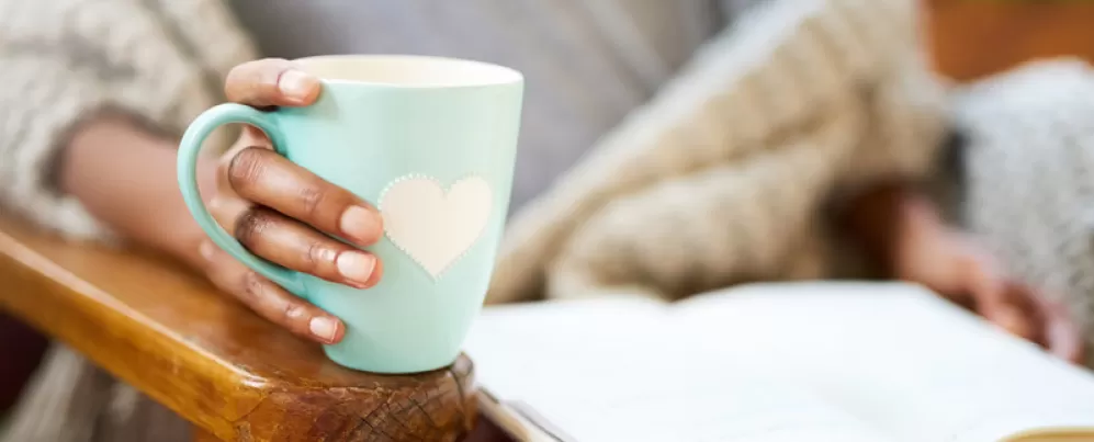 Woman holding mug and reading a book